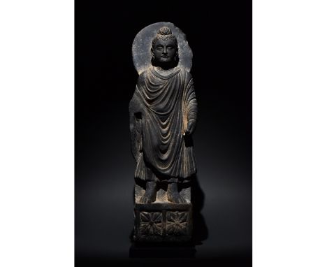 100-300 AD. Gandharan. A grey schist figure of standing Buddha. He is depicted wearing a flowing gown and sporting a topknot 