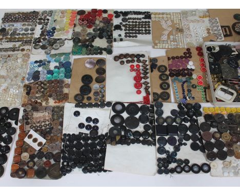 A wooden box containing a quantity of vintage buttons and buckles. 