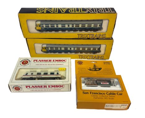 A group of four boxed HO scale models including two Trixtrains British Rail DMU units, a Bachmann Spectrum Plasser EM80C moto