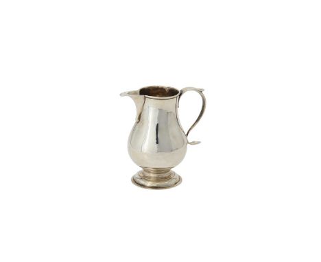 A George III silver baluster cream jug by George Greenhill Jones, London 1729, with a scroll handle and on a circular moulded