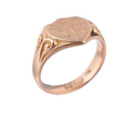 A George V 18 carat gold signet ring, the shield shaped panel engraved with a monogram, to carved scrolled shoulders, hallmar