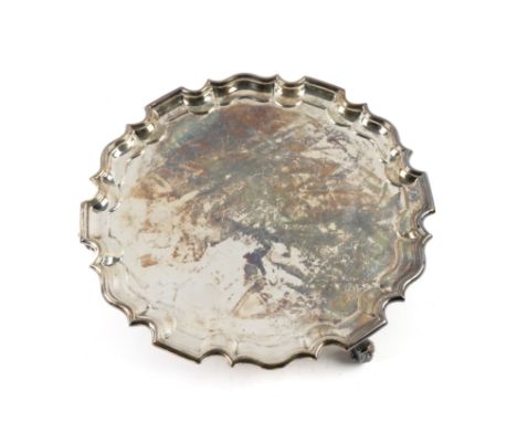 A SILVER SHAPED CIRCULAR SALVERHaving a Chippendale style pie-crust rim, raised on three scrolled feet, in the 18th century t