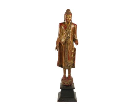 A SOUTH EAST ASIAN GILT-WOOD FIGURE OF A STANDING BUDDHAFirst half 20th Century
Carved wearing robes with paste gems mounted 