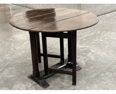 A 17th Century small oak sledge foot drop leaf table of good colour, with chip carved end supports united by a leaf carved st