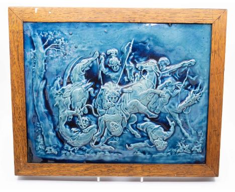 A large Blue glazed ceramic tile with embossed decoration depicting a fight of a lion against soldiers on horseback. In a woo