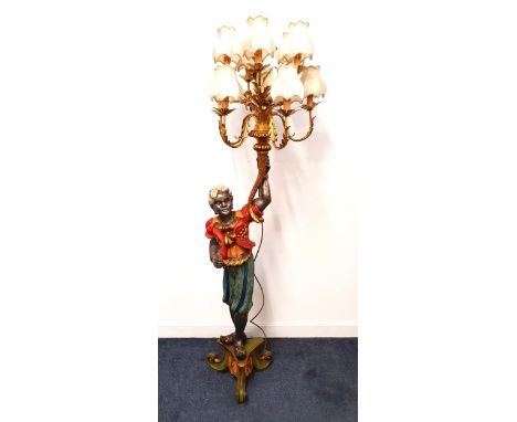 BLACKAMORE FIGURAL LAMPthe carved wood figure raised on a tripod base brightly painted holding a ten gilt branch light aloft 