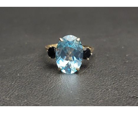 IMPRESSIVE BLUE TOPAZ AND SAPPHIRE THREE STONE RINGthe central oval cut topaz measuring approximately 13.8mm x 9.8mm x 5.9mm,