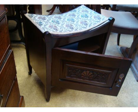 An Edwardian walnut piano stool, with padded dipped seat with cupboard below with carved door. 