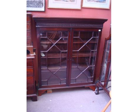 A George III and later astragal glazed bookcase, with fret cut frieze above a pair of doors, raised on bracket feet. 
