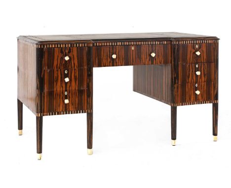 An Art Deco Macassar and ivory-inlaid desk,the inverted front inset with a tooled leather top, over an arrangement of seven d