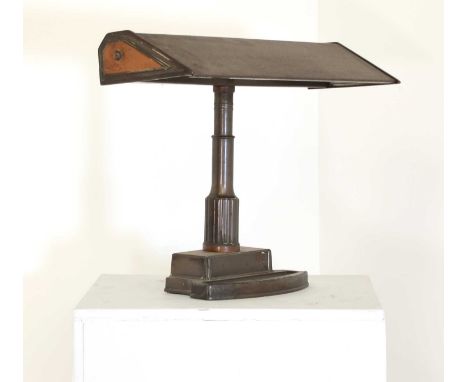 A banker's desk light,with a copper finish, the shade mounted on a tapered column, with a dished plinth,50cm wide36cm highSom