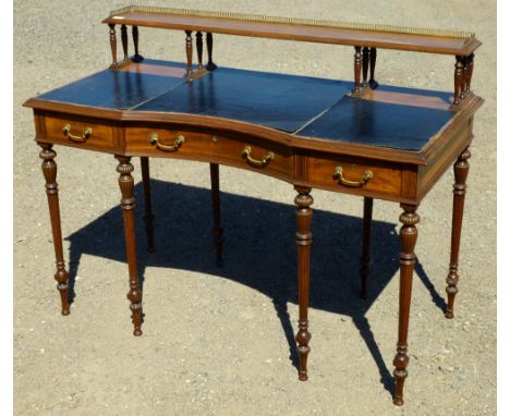 A GOOD EDWARDIAN INLAID MAHOGANY WRITING TABLE, THE CONCAVE TOP WITH THREE DRAWERS AND A GALLERIED SHELF ABOVE, ON REEDED AND