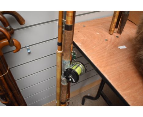 Four vintage fishing rods including fibreglass one has a Penn 150 reel attached