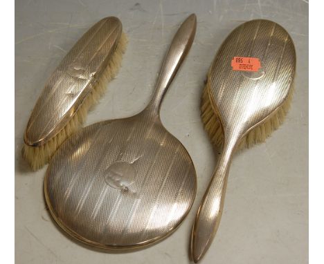 A 1930s silver backed three-piece dressing table set, having engine turned decoration 