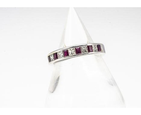 A white metal ruby and diamond half hoop eternity ring, the mixed rectangular cut rubies alternately set with princess cut di
