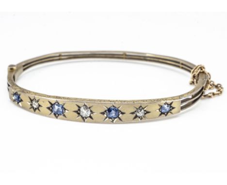 An early 20th Century yellow metal sapphire and diamond bangle, the satin top set with old cut diamonds and oval mixed cut sa