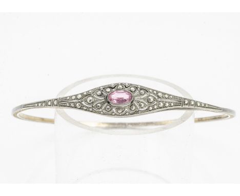 A Belle Epoque costume arm bangle, set with an oval pink paste stone, within a white metal setting and gilt engraved mount, i