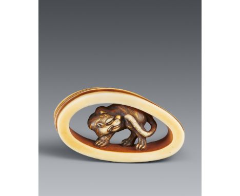 Netsuke eines Tigers in einem Bambusring. Elfenbein, teilweise eingefärbt. Osaka. Um 1860Sign.: Anraku In einem elliptischen 