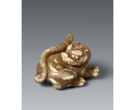 Netsuke eines kleinen Tigers. Elfenbein. Kyoto. 1. Hälfte 19. Jh.Liegend, der große Kopf ist rückwärts gewandt, das eine Vord