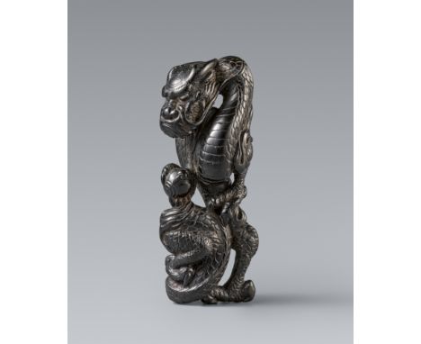 Netsuke eines sich windenden Drachens. Schwarzes Holz. 19. Jh.Aufrecht stehend, in einer dreiklauigen Kralle eine Perle. Eine
