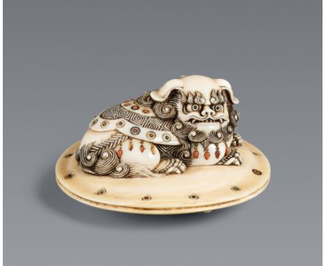 Netsuke eines geschmückten shishi auf Kissen. Elfenbein. Mitte 19. Jh.Auf einem runden Kissen liegt ein nach rechts schauende