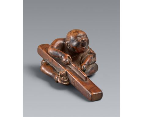 Netsuke eines Schreiners bei der Arbeit. Buchsbaum. Frühes 19. Jh.Sitzend mit einem langen Balken, den er mit den Füßen festh