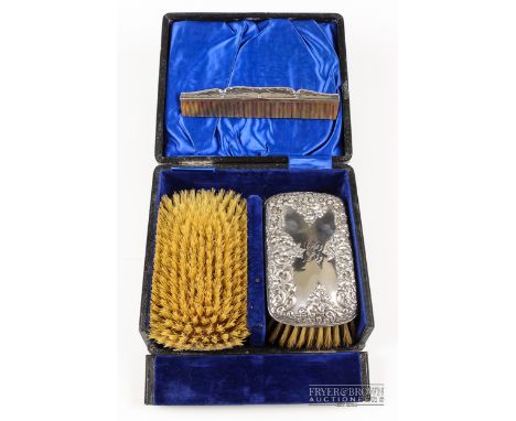 A set of two silver backed brushed with conforming comb, repousse decorated with scrolling floral foliage, makers mark Deacon