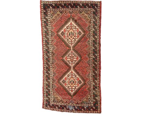 A Shiraz carpet, mid 20th century,  The madder field with an ivory triple linked medallion, with rows of stylised plants, wit