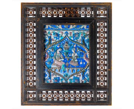 A large Persian Qajar painted moulded pottery tile, 19th century. The central medallion enclosing two seated female figures, 