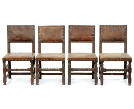 A set of four oak chairs, early 20th c, in Charles I style, the padded back and stuffed over seat covered in brass nailed hid