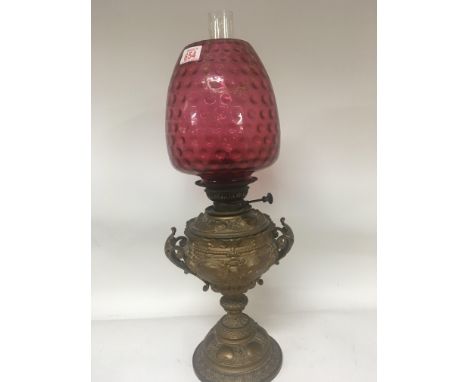 A Victorian oil lamp with an elaborate Spelter base and cranberry shade damaged.