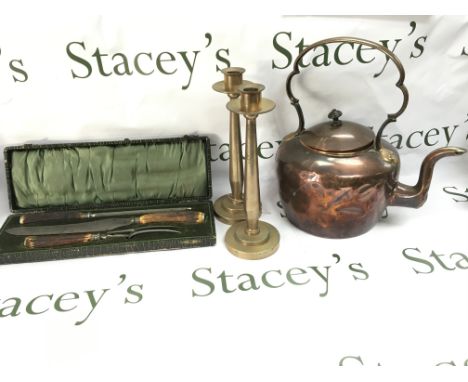 A copper kettle pair of heavy candlestick holders and a cased carving set.