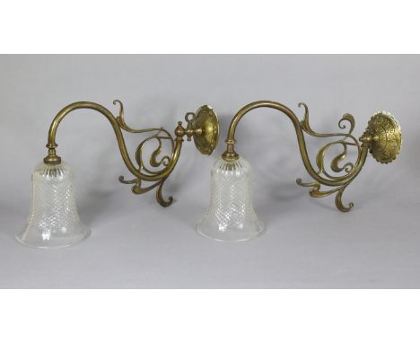 A pair of Art Nouveau oxidised brass wall-mounted gas lights, each with clear cut glass bell-shaped shade. 