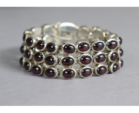 A silver flexible bracelet of three rows set amethyst-coloured cabochons.
