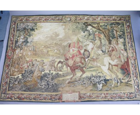 A Flemish-style French tapestry titled “Le Canal De Bruges”, depicting soldiers on horse-back riding into battle, 103” wide x