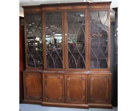 A 19th century inlaid mahogany break-front bookcase with a moulded cornice above nine adjustable shelves enclosed by glazed p