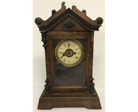 A vintage wooden cased mantel clock with pendulum and partial retailer original label to back.  Decorative detail to top with