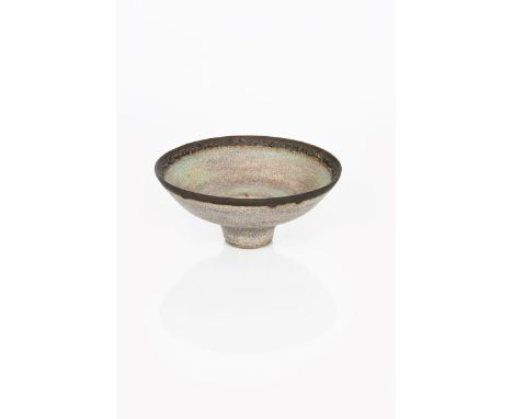 ‡ Dame Lucie Rie (1902-1995) a stoneware footed bowl, covered in a heather glaze, circa 1980, pitted purple and turquoise-blu