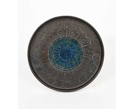 A Troika Pottery tray, circular with raised rim, resist decorated with a radiating design in blue on a manganese ground, impr