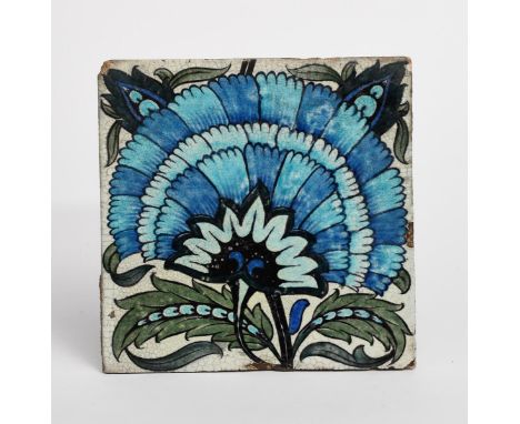 A William De Morgan Sands End Pottery large tile, painted with a fan flower in blue, green and black on a white ground, impre