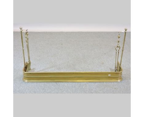 An Edwardian brass fender, 126cm, with a set of turned brass fire tools