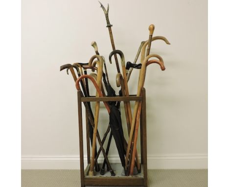 A collection of various walking sticks, together with a stick stand