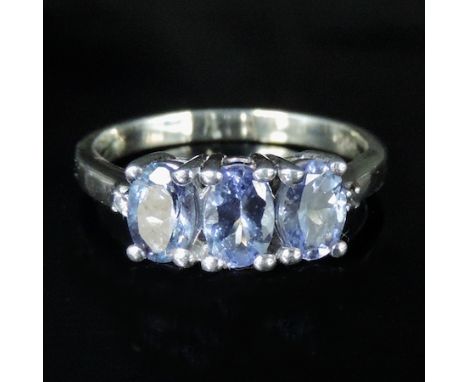 An 18 carat white gold three stone tanzanite and diamond ring, boxed