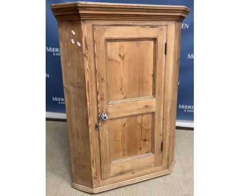 A 19th Century pine hanging corner cupboard, the two panel door opening to reveal a shaped fretwork carved two shelf interior