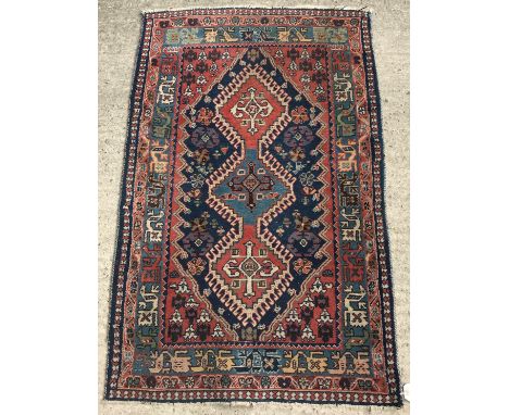 A Caucasian type rug, the central panel set with three joined lozenge medallions on a blue and red ground with stylised anima