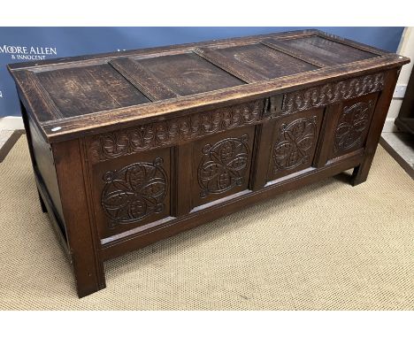 An 18th Century oak coffer, the plain four panel top with moulded stiles over a foliate medallion carved frieze and four foli