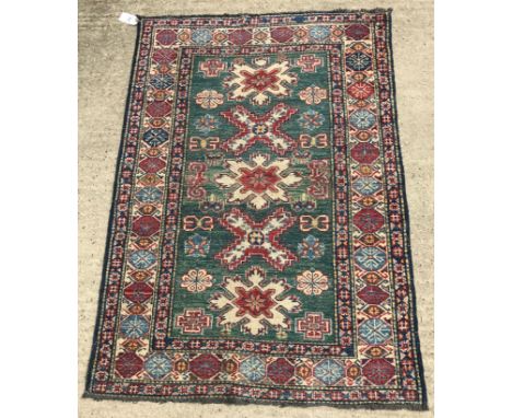 A Caucasian style rug, the central panel set with cross type medallions on a green ground, within a stepped red, blue and cre