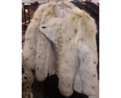 An ermine cape, two other fur capes, a white and light brown spotted fox fur jacket and an ocelot fur cape