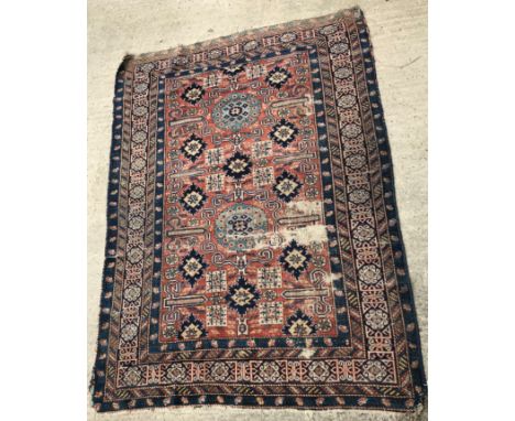 A Caucasian Shirvan rug, the central panel set with scrolling geometric and stylised flower head motifs on a red ground, with