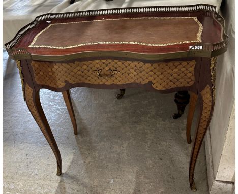 A 20th Century mahogany and marquetry inlaid writing table in the Louis XVI taste, the shaped top with brass gallery and tool